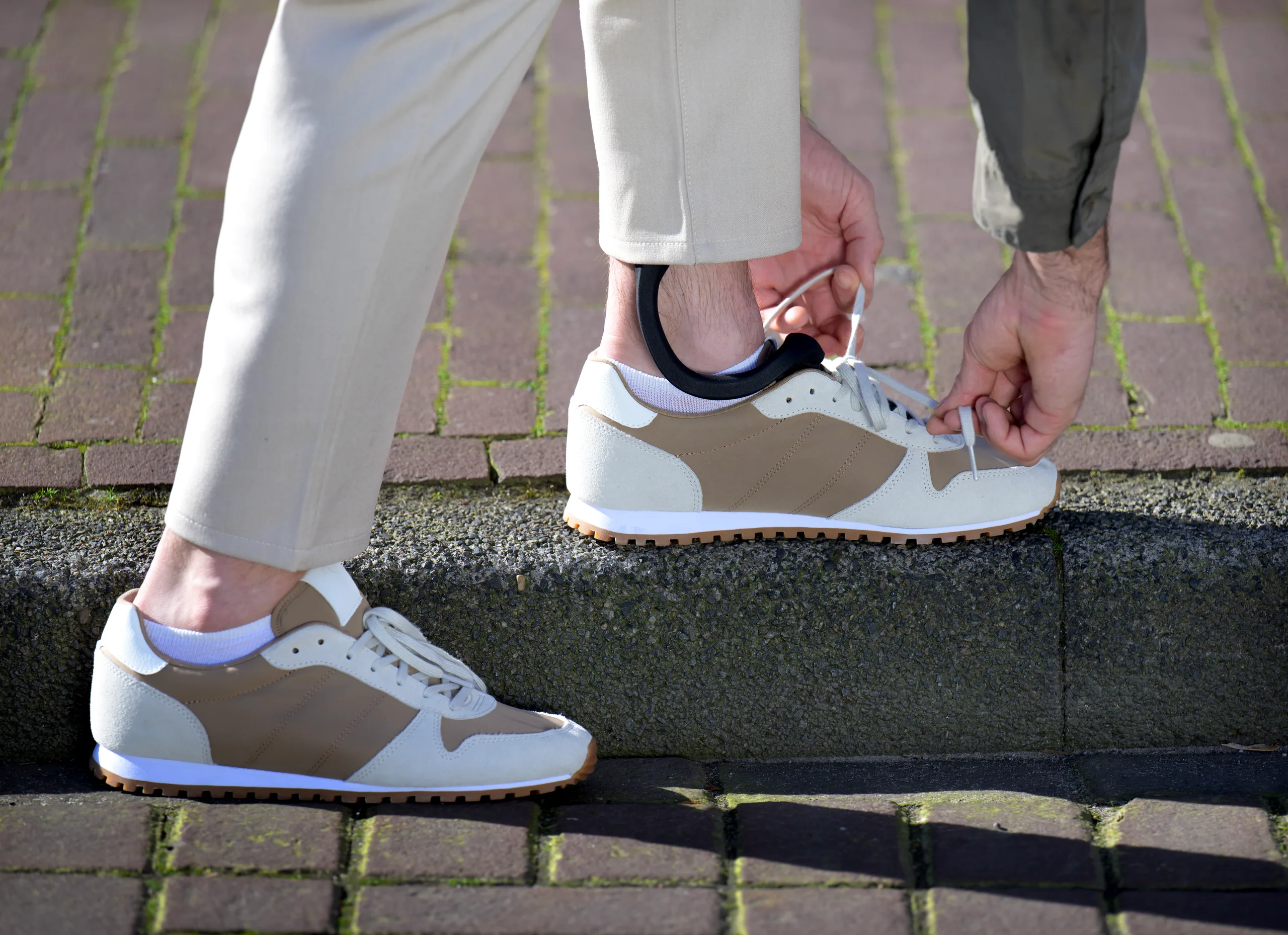 A close-up of tying a shoe with The Rise brace visible, showing it fits inside regular footwear